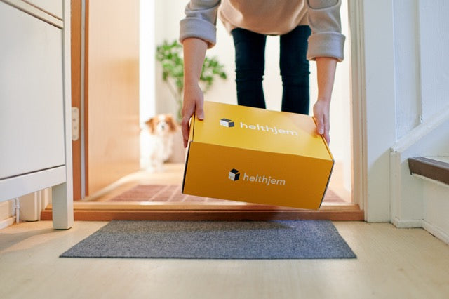 Person picking a yellow box with 'helthjem' branding