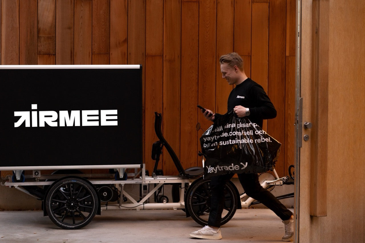 Delivery person with a bag walking past a vehicle with 'Airmee' branding.