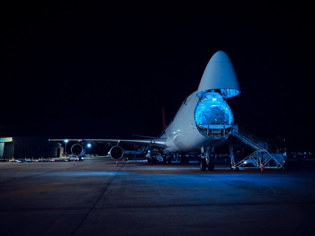 Airplane on a runway at night with blue lighting. Filling up with cargo.