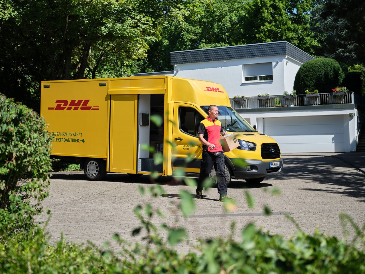DHL delivery van with a driver in front of a house