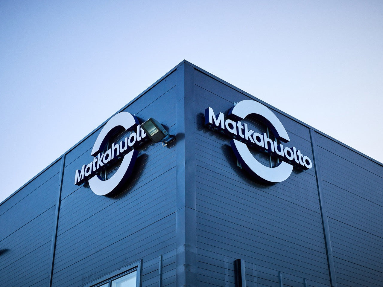 Matkahuolto logo on a building corner with a clear sky background
