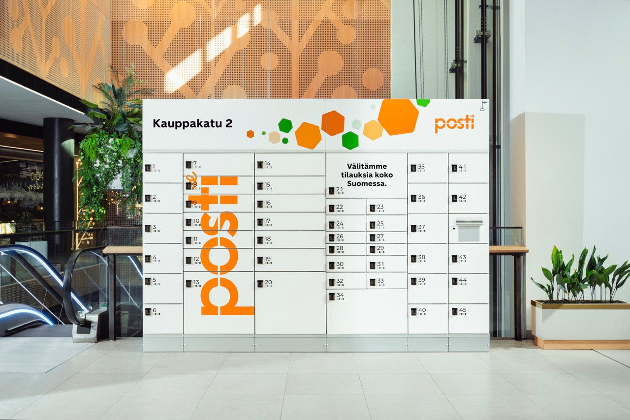 Posti locker system in a modern indoor setting with plants and escalator.
