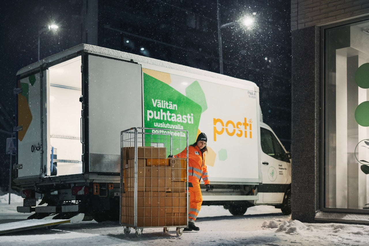 Posti delivery truck with a worker loading boxes at night.