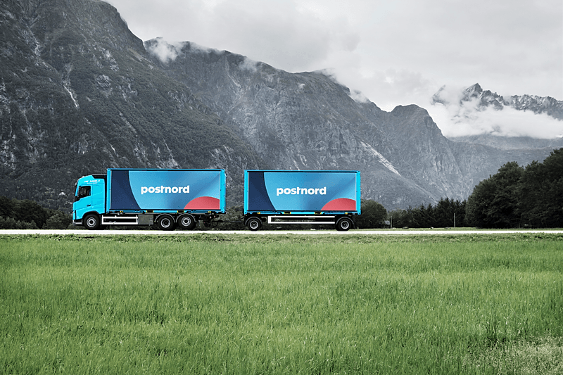 PostNord truck on road with hills on the background