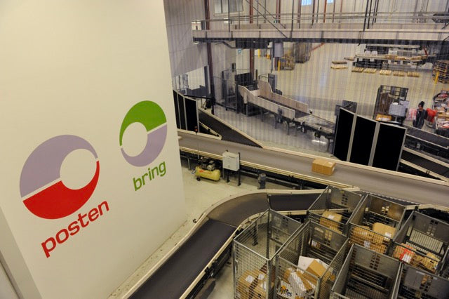 Logistics center with conveyor belts and 'posten' and 'bring' logos on a wall.